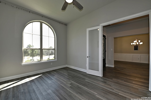 empty room with dark hardwood / wood-style floors and ceiling fan with notable chandelier