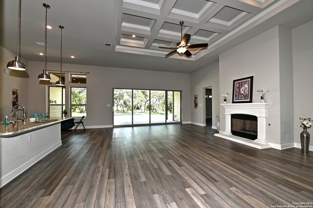 unfurnished living room with dark hardwood / wood-style floors, ceiling fan, beam ceiling, a towering ceiling, and coffered ceiling