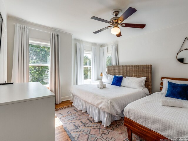 bedroom with light wood-type flooring, ceiling fan, and multiple windows