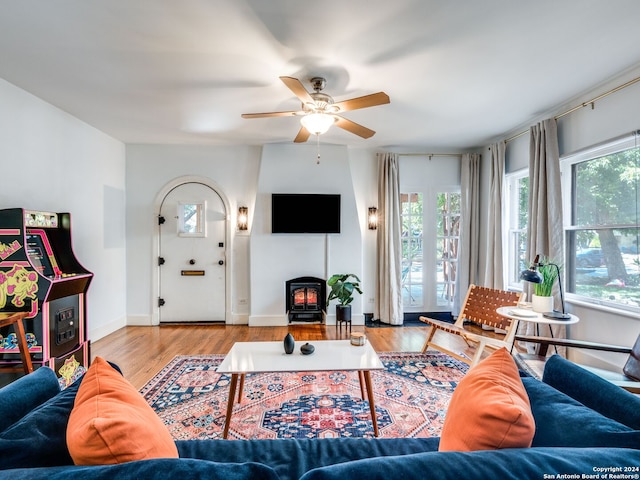 living room featuring ceiling fan, a wood stove, and light hardwood / wood-style floors