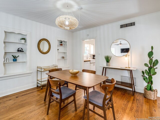 dining room featuring built in shelves, a chandelier, and hardwood / wood-style floors