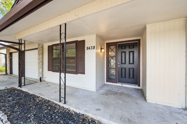 view of exterior entry featuring a garage and a porch