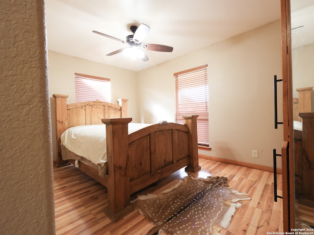 bedroom featuring light wood-type flooring, ceiling fan, and multiple windows