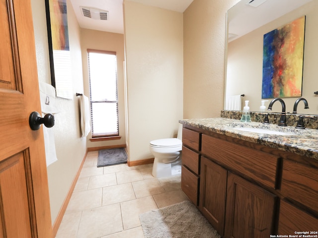 bathroom featuring vanity, toilet, plenty of natural light, and tile patterned flooring