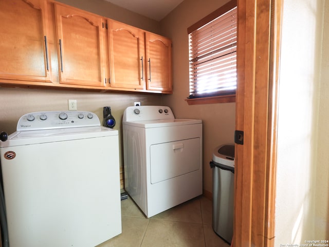 clothes washing area with cabinets, light tile patterned floors, and independent washer and dryer