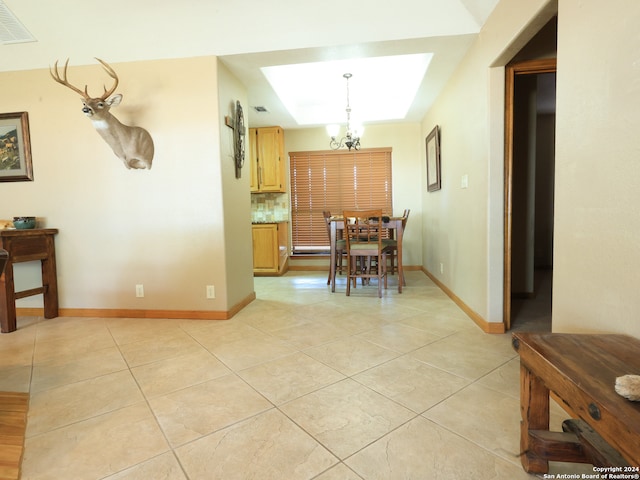 tiled dining area featuring an inviting chandelier and a raised ceiling