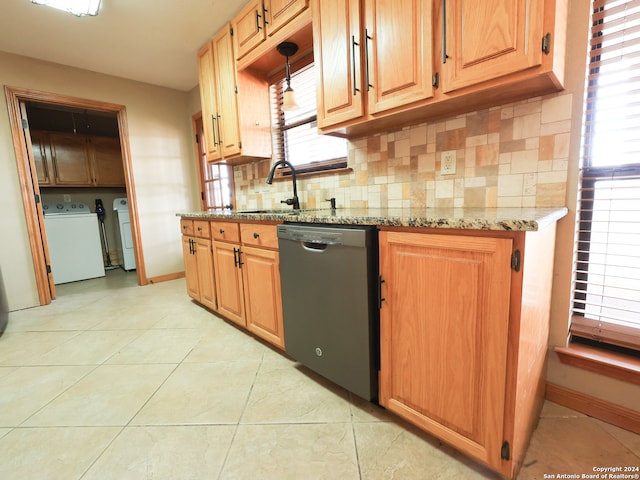 kitchen with pendant lighting, light tile patterned flooring, black dishwasher, washer / dryer, and light stone counters