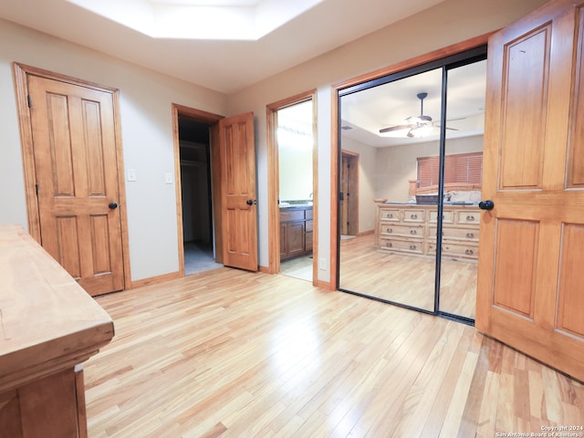 bedroom with ceiling fan, ensuite bath, and light hardwood / wood-style floors