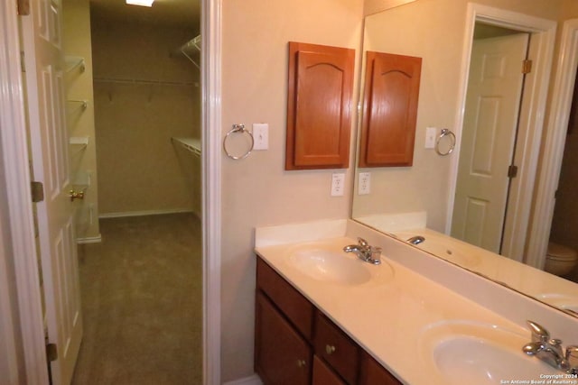 bathroom with double vanity, a sink, and toilet