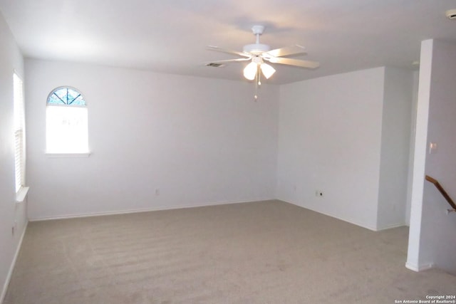 unfurnished room with light carpet and a ceiling fan