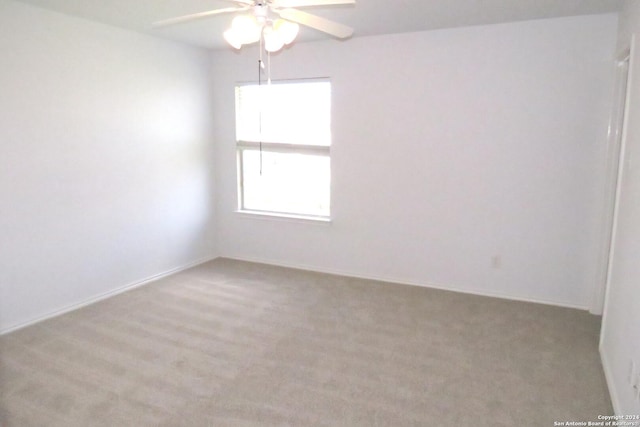 unfurnished room featuring a ceiling fan, light colored carpet, and baseboards