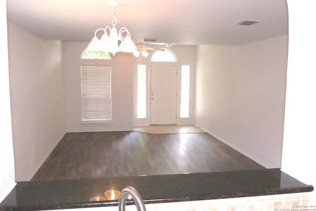 entryway with baseboards, dark wood finished floors, visible vents, and an inviting chandelier