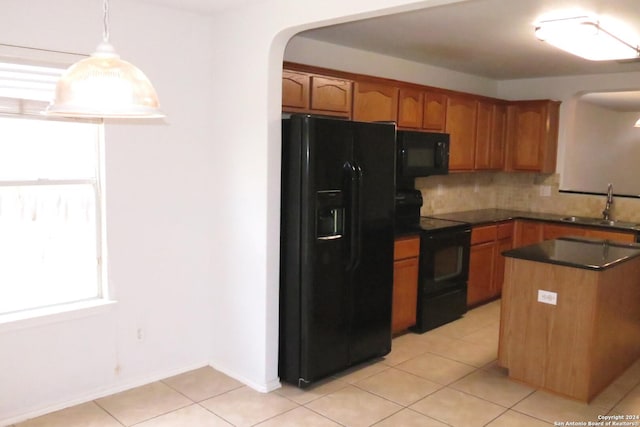 kitchen with a sink, hanging light fixtures, backsplash, black appliances, and dark countertops