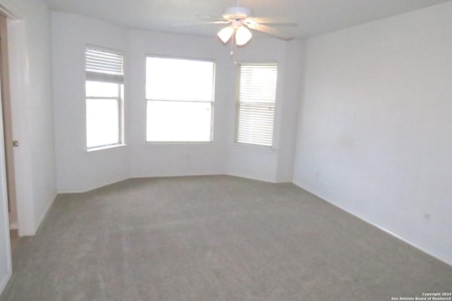 unfurnished room featuring ceiling fan, light colored carpet, and a healthy amount of sunlight