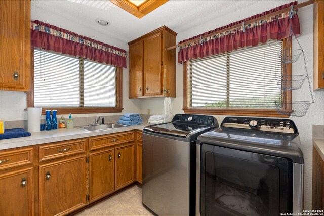 laundry room with light tile patterned floors, washing machine and dryer, cabinets, and sink