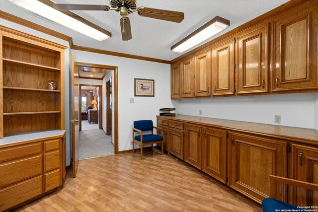 kitchen with ceiling fan, light wood-type flooring, ornamental molding, and a textured ceiling