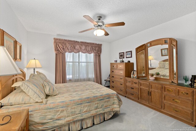 bedroom with a ceiling fan, a textured ceiling, and light colored carpet