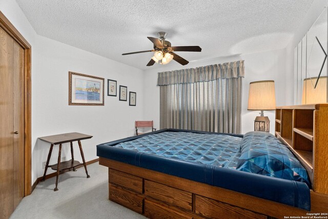 bedroom with ceiling fan, a textured ceiling, light carpet, baseboards, and a closet