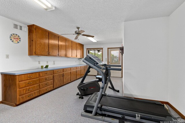 workout area featuring ceiling fan, a textured ceiling, and light colored carpet