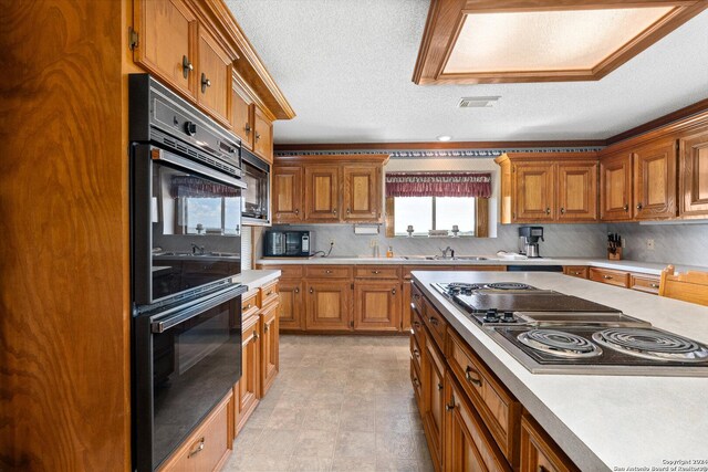 kitchen with black appliances, backsplash, a textured ceiling, and light tile patterned floors