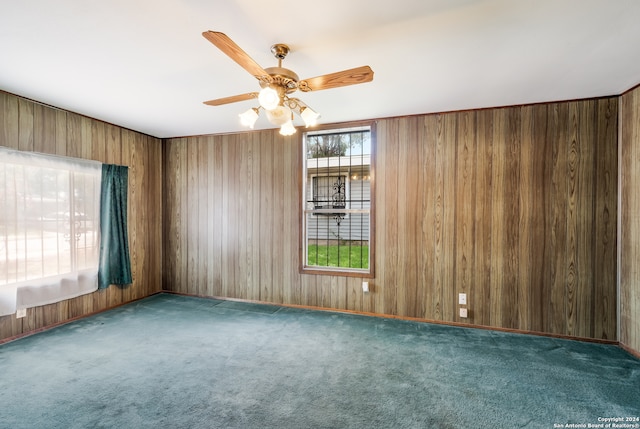 carpeted empty room featuring ceiling fan and wood walls