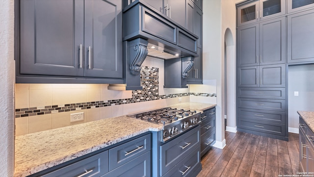 kitchen featuring light stone counters, decorative backsplash, dark hardwood / wood-style floors, and stainless steel gas stovetop