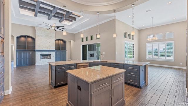 kitchen featuring a fireplace, coffered ceiling, beamed ceiling, a kitchen island, and sink