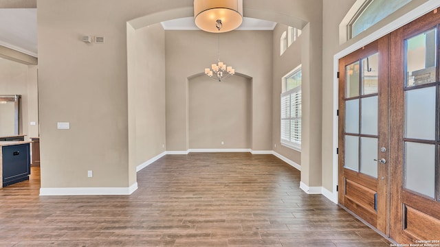 foyer entrance with french doors, an inviting chandelier, hardwood / wood-style flooring, and a high ceiling