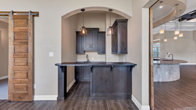 kitchen featuring kitchen peninsula, a barn door, dark hardwood / wood-style flooring, and a breakfast bar area