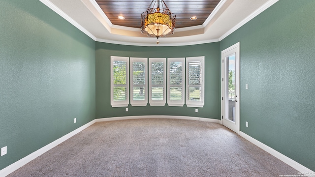 spare room with a tray ceiling, carpet flooring, and crown molding