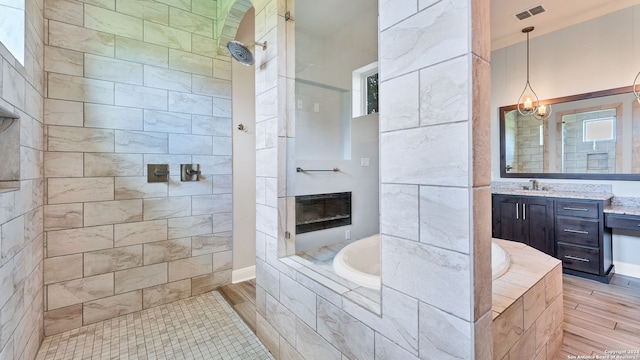 bathroom featuring hardwood / wood-style flooring, vanity, and plus walk in shower