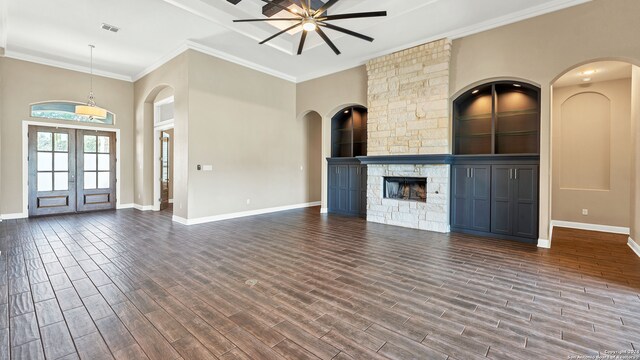 unfurnished living room featuring french doors, a fireplace, crown molding, ceiling fan, and dark hardwood / wood-style floors