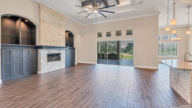 unfurnished living room featuring a fireplace, a tray ceiling, dark hardwood / wood-style floors, and ornamental molding