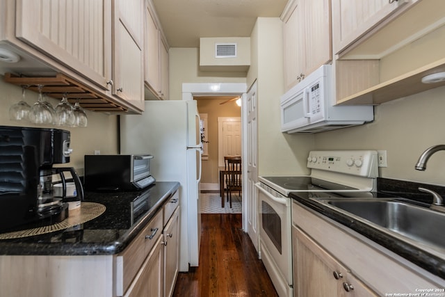 kitchen featuring light brown cabinets, dark stone counters, dark wood-type flooring, white appliances, and sink