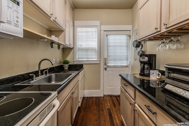 kitchen featuring dark stone countertops, light brown cabinetry, white appliances, dark hardwood / wood-style floors, and sink