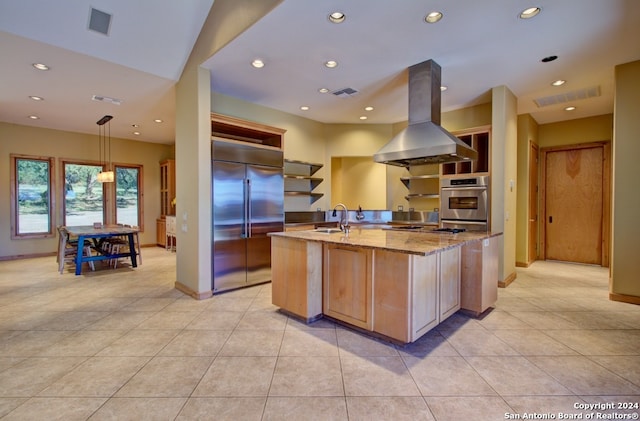 kitchen with sink, hanging light fixtures, appliances with stainless steel finishes, island range hood, and light stone counters