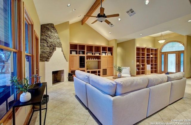 tiled living room featuring ceiling fan, high vaulted ceiling, a stone fireplace, and beam ceiling