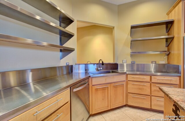 kitchen with light tile patterned flooring, stainless steel dishwasher, stainless steel counters, and sink