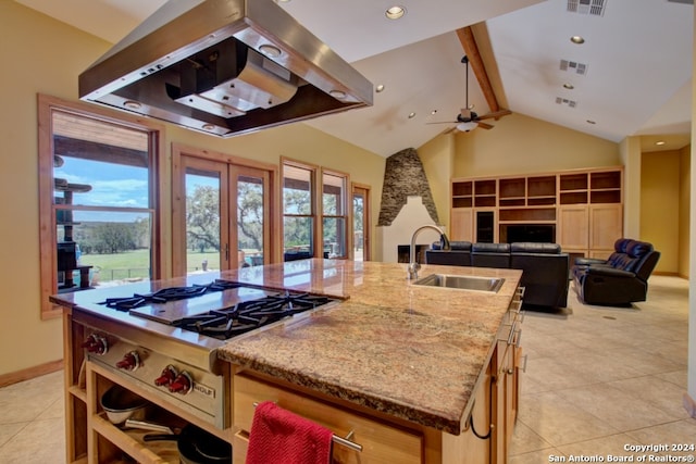 kitchen featuring sink, beamed ceiling, an island with sink, stainless steel gas stovetop, and island range hood