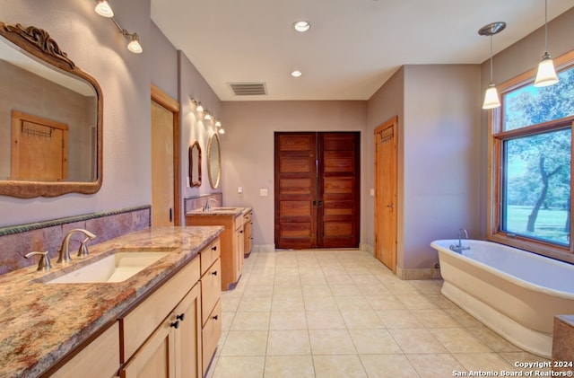 bathroom with a bathing tub, tile patterned flooring, and vanity