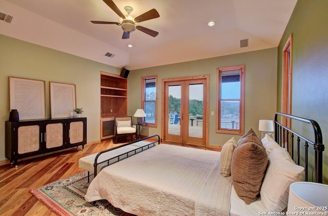 bedroom with vaulted ceiling, light wood-type flooring, a raised ceiling, french doors, and access to exterior