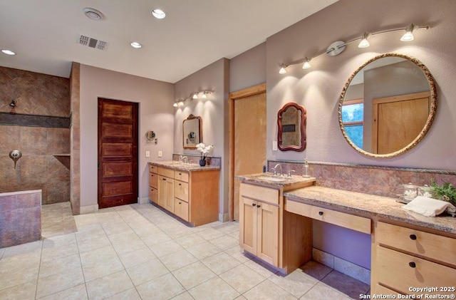 bathroom featuring tile patterned floors, a tile shower, and vanity