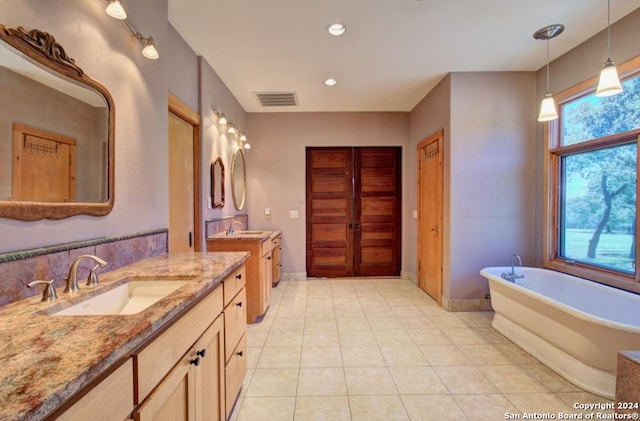 bathroom featuring a washtub, tile patterned flooring, and vanity