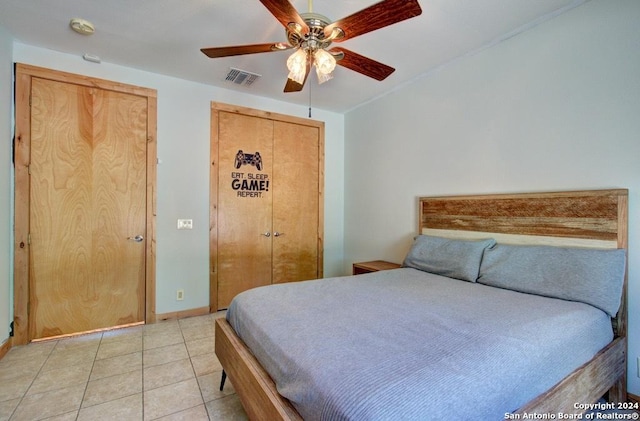 tiled bedroom with ceiling fan and a closet