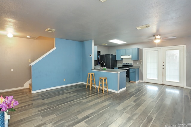 kitchen with ceiling fan, electric stove, black refrigerator, and hardwood / wood-style flooring