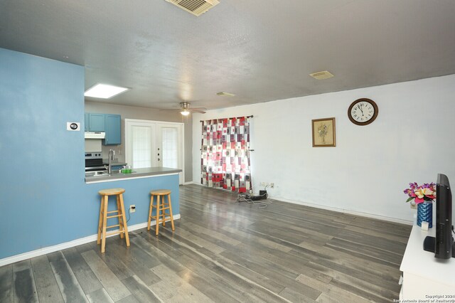 kitchen with stove, hardwood / wood-style floors, a kitchen bar, blue cabinets, and ceiling fan