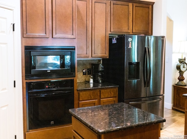 kitchen featuring dark stone countertops, light tile patterned floors, decorative backsplash, a kitchen island, and black appliances