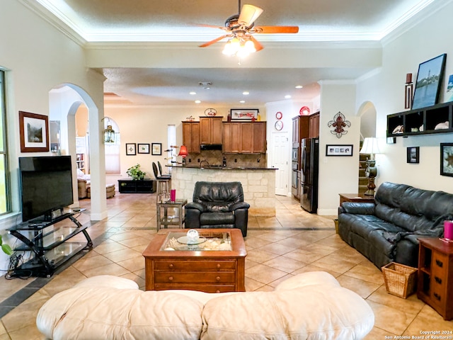 tiled living room with ornamental molding and ceiling fan