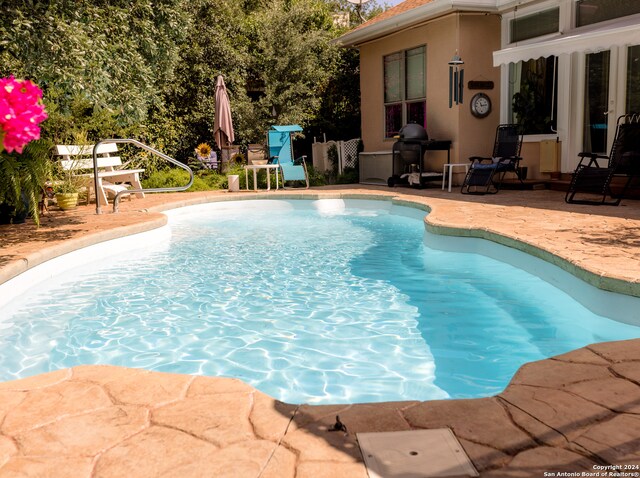 view of swimming pool with grilling area and a patio area