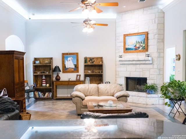 living room with crown molding, a textured ceiling, ceiling fan, tile patterned flooring, and a fireplace